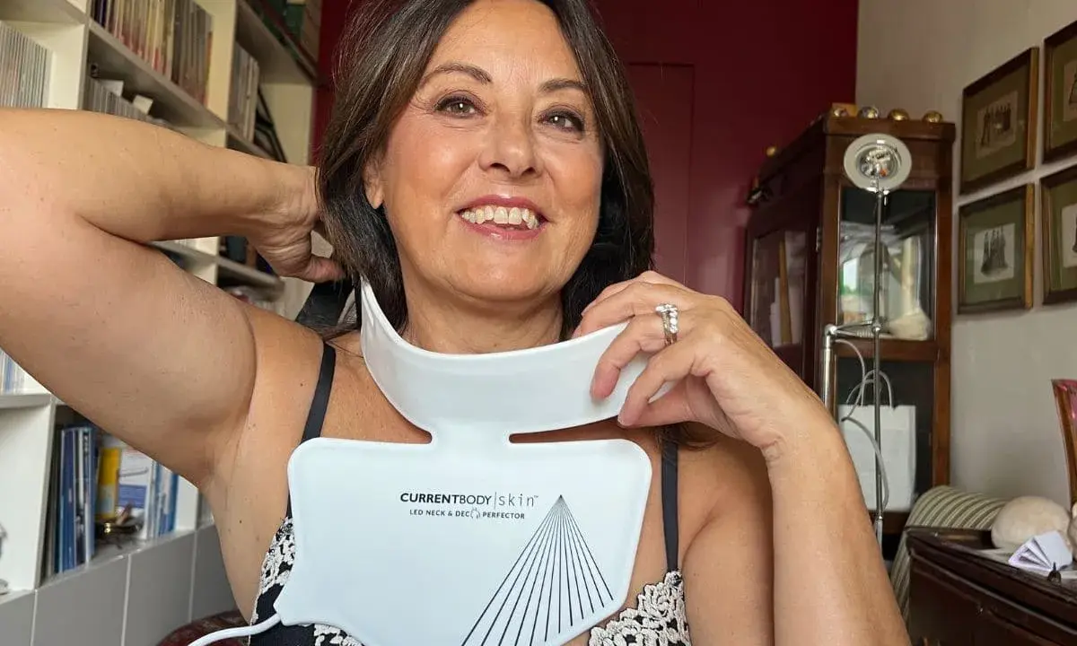 Donna sorridente prova un dispositivo LED per collo e décolleté, una soluzione per le rughe décolleté come eliminarle.