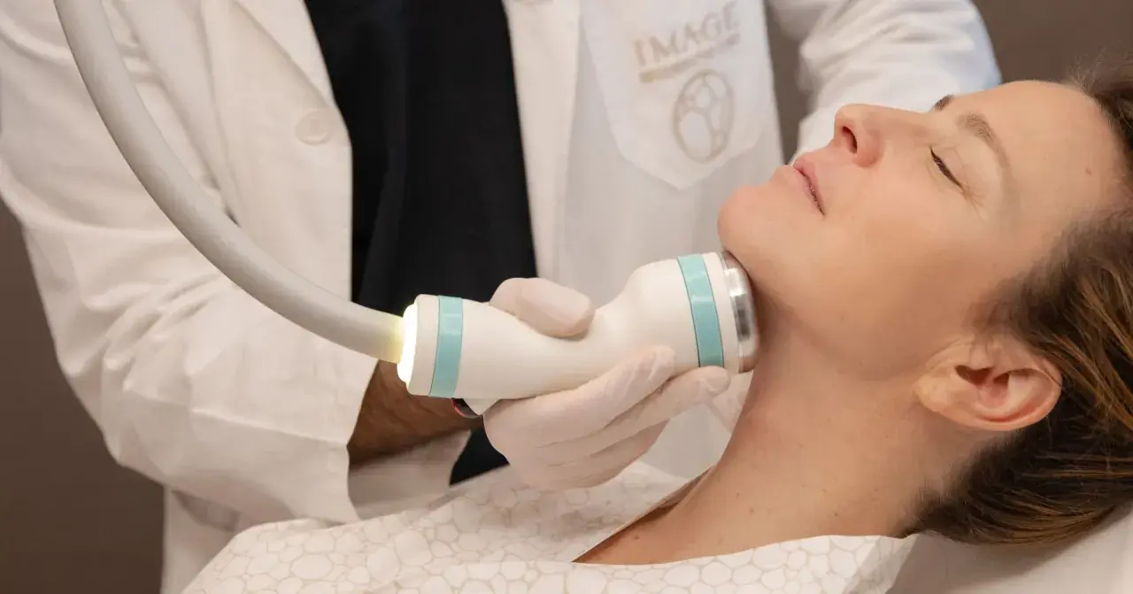 Medico esegue trattamento onda coolwaves sul collo di una donna per migliorare l'aspetto della pelle.