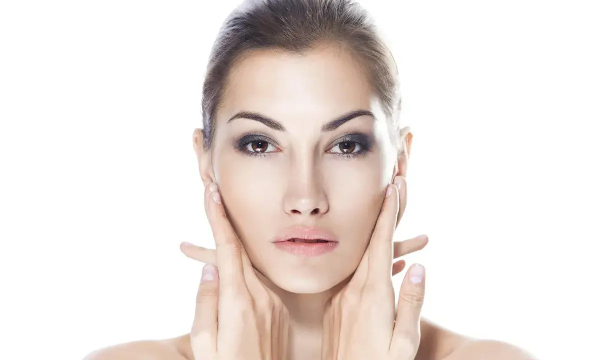 Viso di donna con mani che accarezzano le guance. Ci si chiede: dermamelan dopo quanto fa effetto per una pelle perfetta?