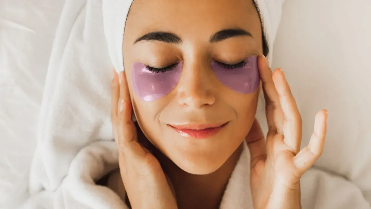 Donna con impacchi viola sotto gli occhi, un rituale di bellezza con punture di vitamine per occhiaie.
