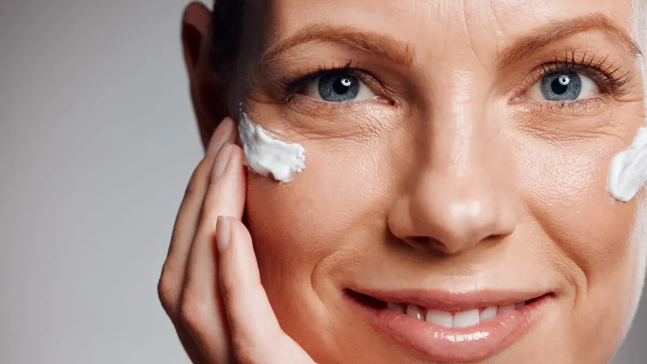 Primo piano di un volto femminile con crema applicata vicino all'occhio, per contrastare il danno attinico.