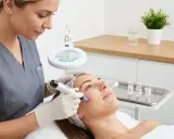 Estetista usa Dermapen per trattamento viso. Si parla di esosomi cosa sono, piccole vescicole che trasportano molecole benefiche per la pelle.