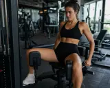 Donna si allena in palestra, concentrata sull'esercizio per l'interno coscia.