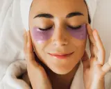 Donna con impacchi viola sotto gli occhi, un rituale di bellezza con punture di vitamine per occhiaie.