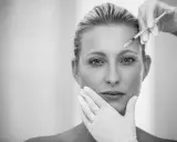 Ritocchino per combattere i segni del tempo e del sole. Botox sulla fronte, mani guantate che accarezzano il viso.