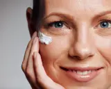Primo piano di un volto femminile con crema applicata vicino all'occhio, per contrastare il danno attinico.