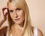 Giovane donna con lentiggini, capelli biondi e sguardo intenso. Immagina un trattamento di pico laser viso per una pelle radiosa.