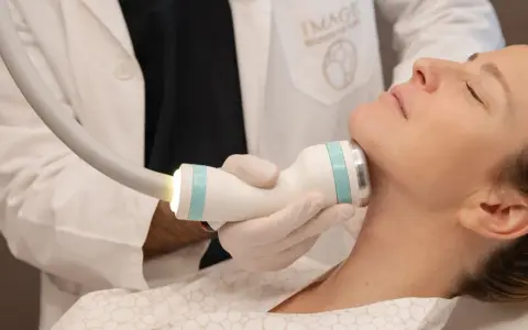 Medico esegue trattamento onda coolwaves sul collo di una donna per migliorare l'aspetto della pelle.