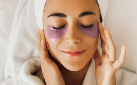 Donna con impacchi viola sotto gli occhi, un rituale di bellezza con punture di vitamine per occhiaie.