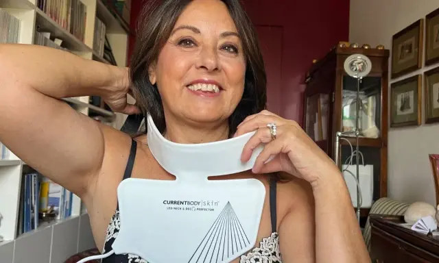 Donna sorridente prova un dispositivo LED per collo e décolleté, una soluzione per le rughe décolleté come eliminarle.