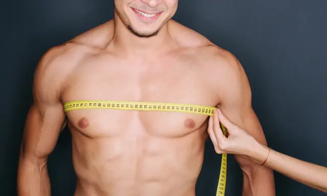 Uomo sorridente con metro da sarto intorno al petto, un passo per eliminare grasso petto uomo.