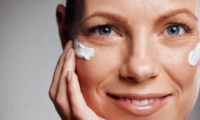 Primo piano di un volto femminile con crema applicata vicino all'occhio, per contrastare il danno attinico.