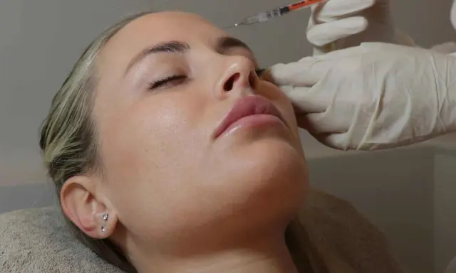 Primo piano del **full face viso** di una donna con gli occhi chiusi, mentre una mano guantata le inietta un filler sul naso.