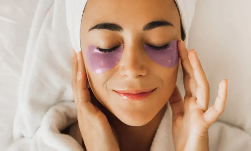 Donna con impacchi viola sotto gli occhi, un rituale di bellezza con punture di vitamine per occhiaie.