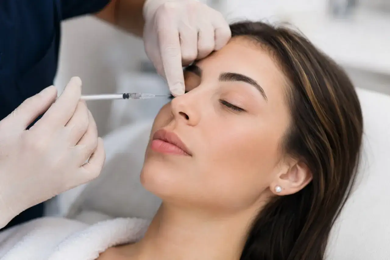 Primo piano di una donna che riceve un rinofiller naso frontale. Un medico con guanti in lattice inietta delicatamente un filler nella zona del naso.