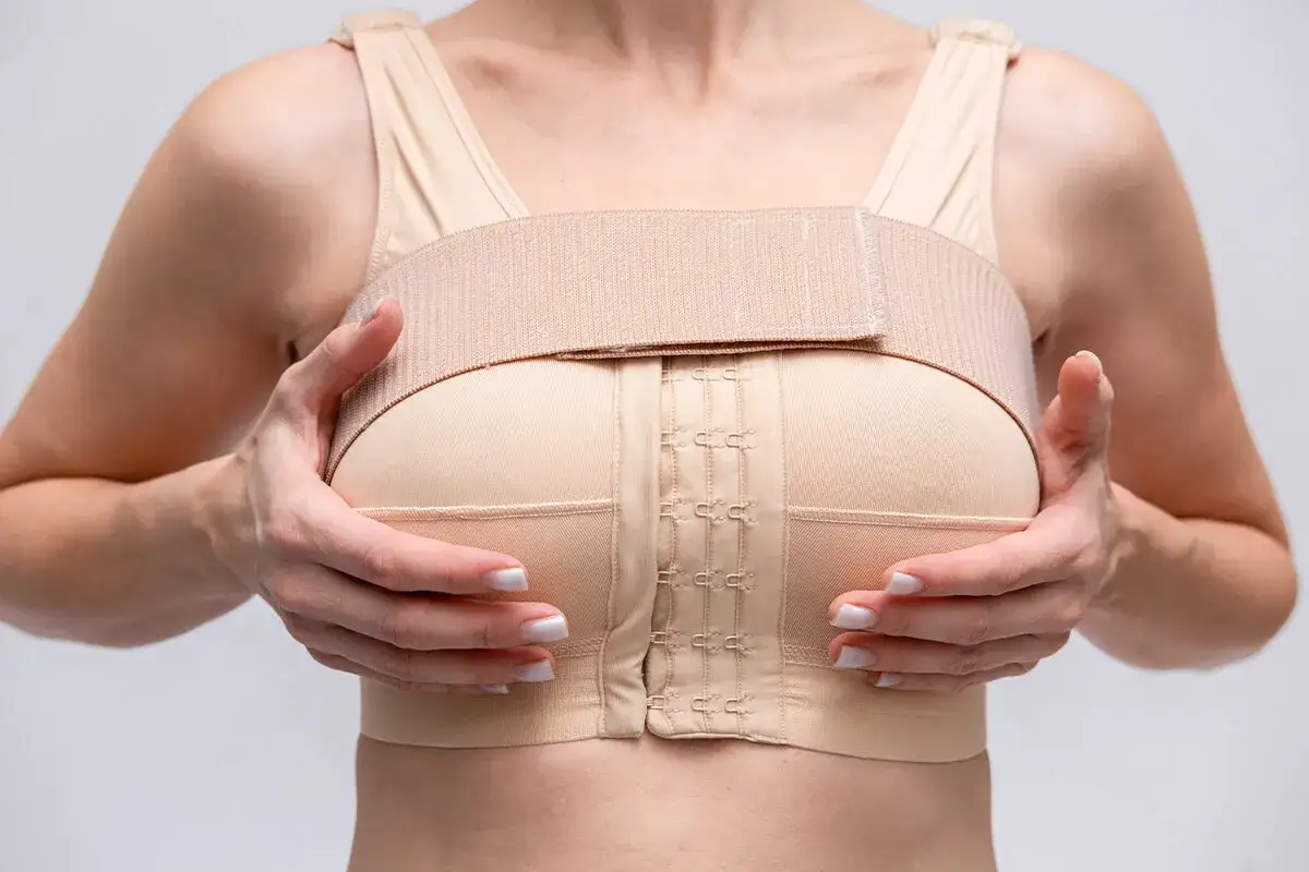 Donna con reggiseno post-operatorio, essenziale per la riduzione seno e tempi di recupero ottimali.