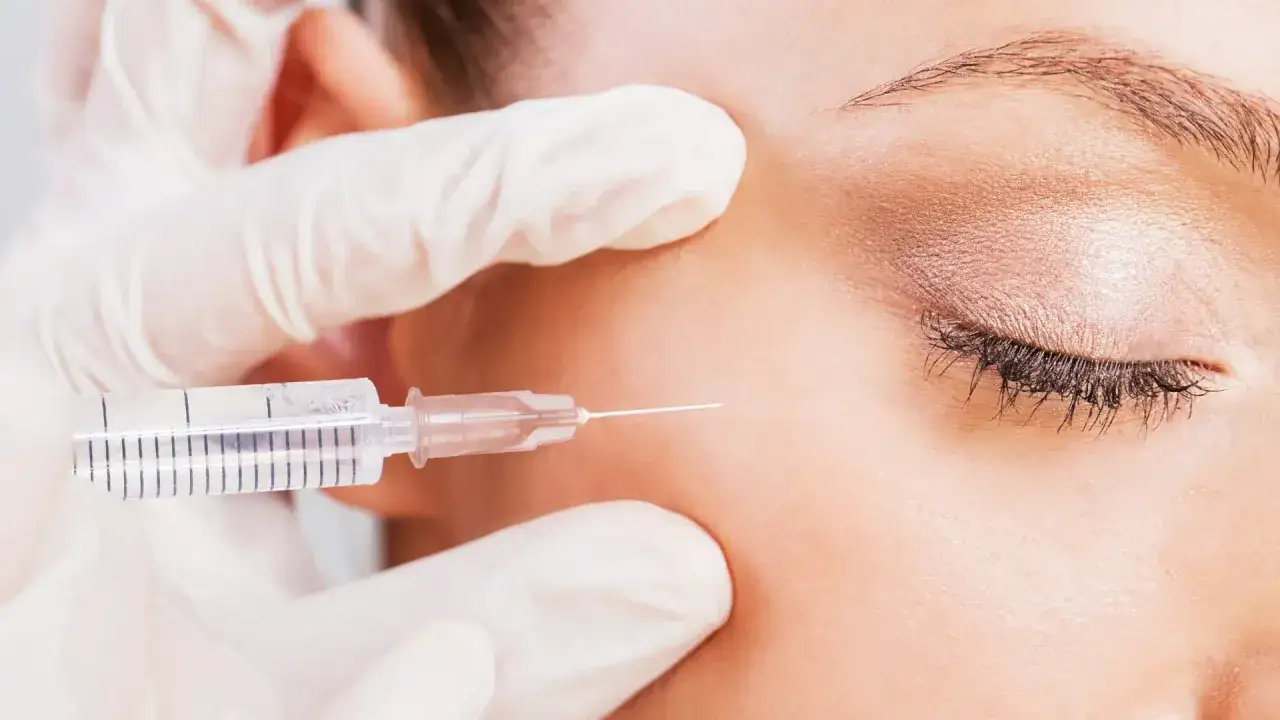 Mano guantata esegue punture di vitamine per occhiaie, un trattamento estetico mirato a migliorare l'aspetto della pelle.