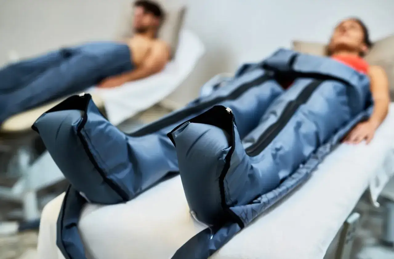 Persone sdraiate ricevono un trattamento di pressoterapia, con gambe avvolte in speciali manicotti gonfiabili che illustrano come funziona la pressoterapia per migliorare la circolazione.
